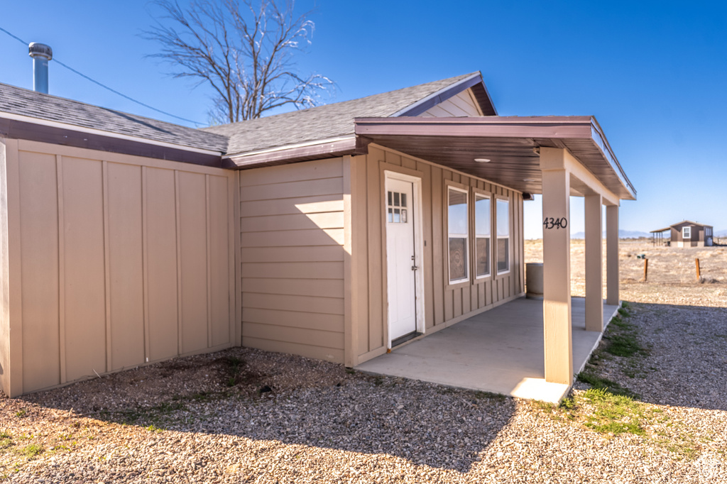 View of side of property with a shingled roof, a patio area, and board and batten siding