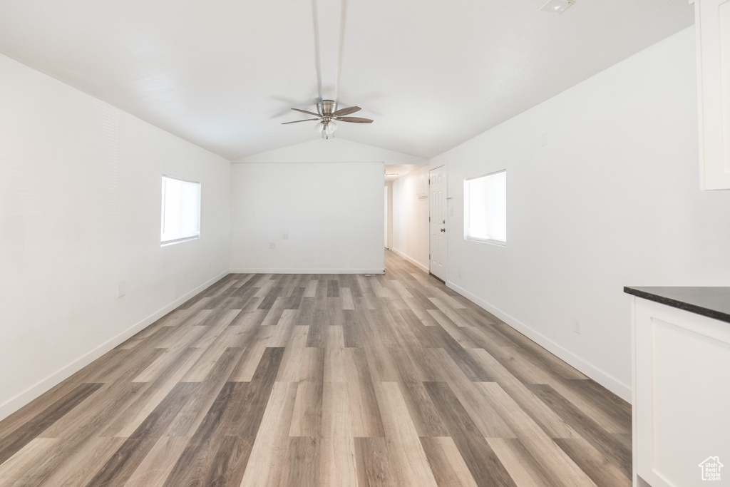 Unfurnished living room featuring ceiling fan, vaulted ceiling, and light wood-style flooring