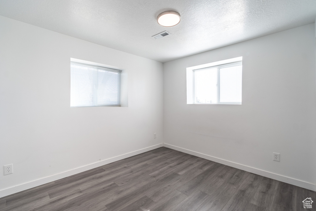 Unfurnished room with dark wood-style flooring and a textured ceiling
