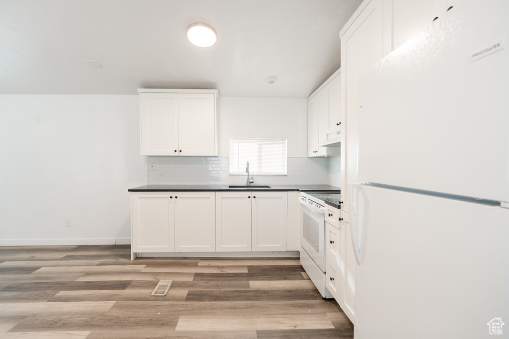 Kitchen featuring white appliances, white cabinets, and dark countertops