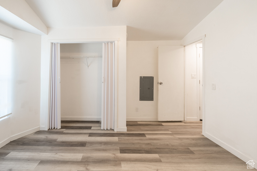 Unfurnished bedroom with electric panel, wood finished floors, a closet, and ceiling fan