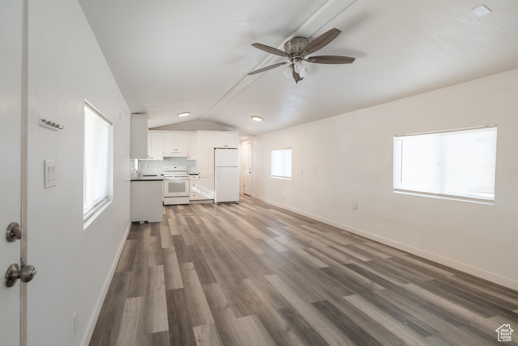 Unfurnished living room with ceiling fan, lofted ceiling, and wood finished floors