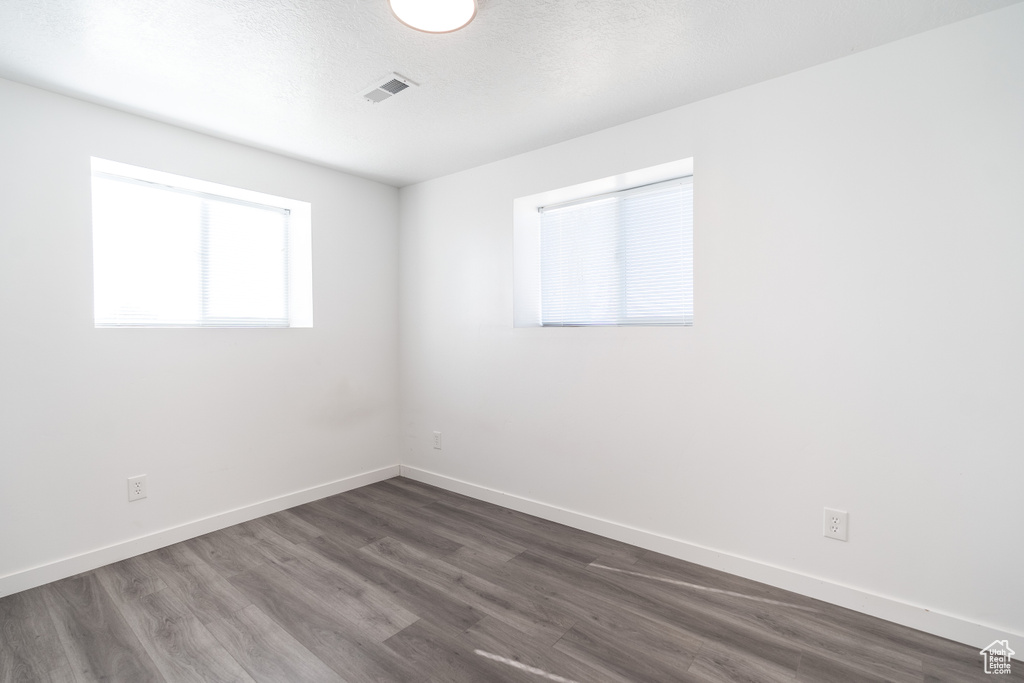 Empty room with dark wood-style flooring and baseboards