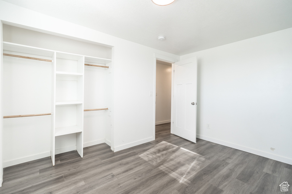 Unfurnished bedroom with wood finished floors and a closet
