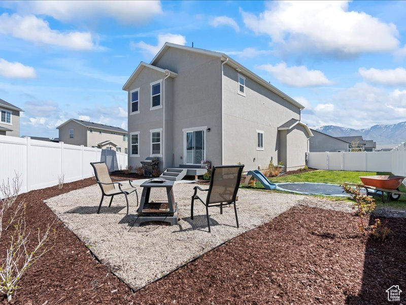 Back of house with stucco siding, a fenced backyard, a patio area, and a mountain view