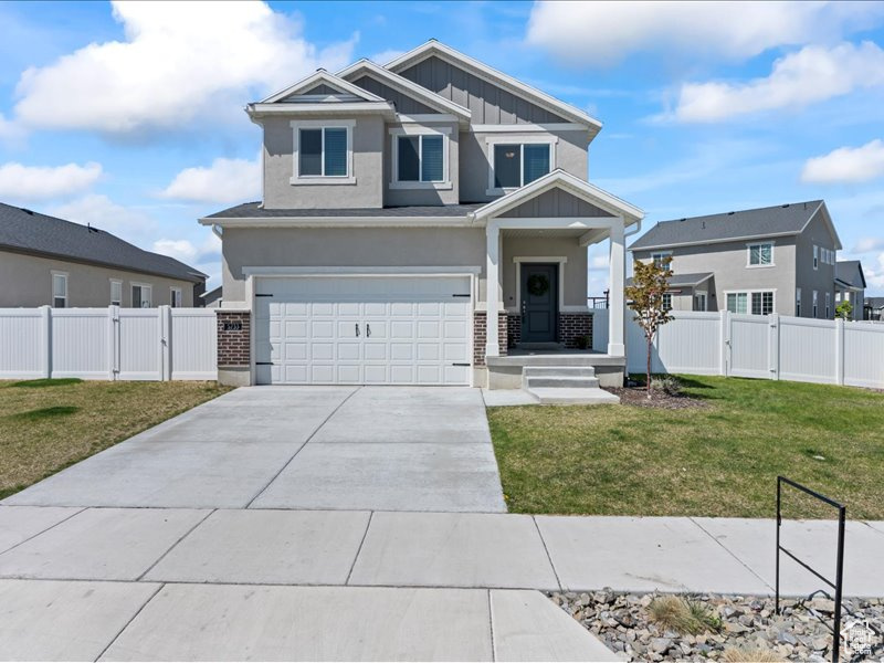 Craftsman-style home featuring a gate, an attached garage, board and batten siding, driveway, and stucco siding