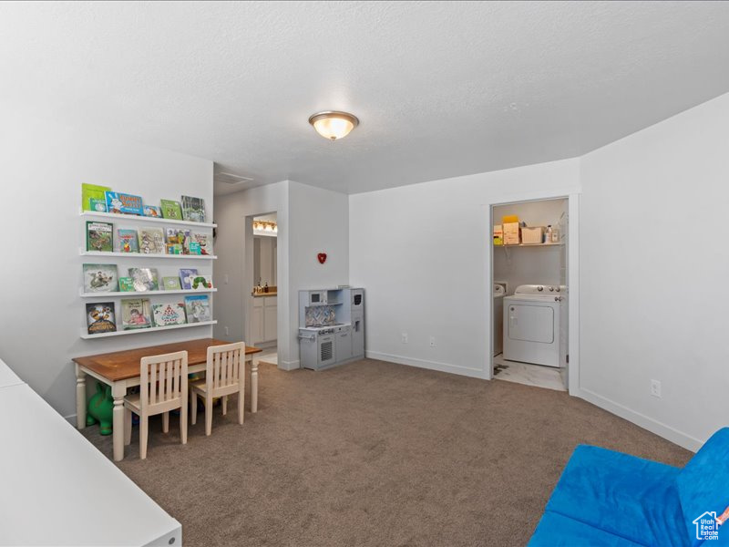 Playroom featuring washer and clothes dryer, carpet floors, and a textured ceiling