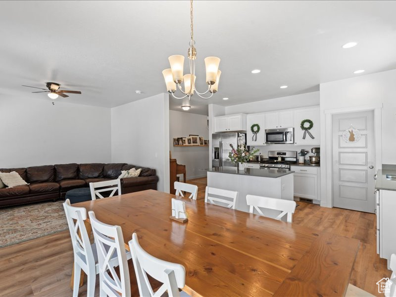 Dining space featuring light wood finished floors, a chandelier, ceiling fan, and recessed lighting