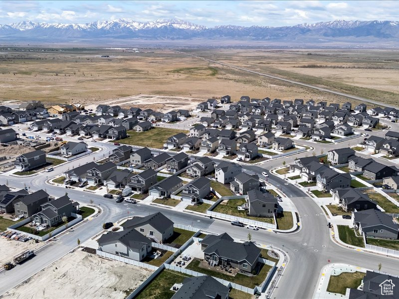Aerial view of property and surrounding area featuring nearby suburban area and a mountainous background