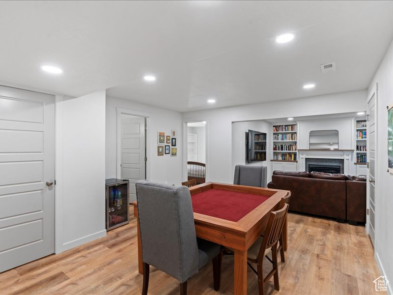 Dining area with light wood finished floors, beverage cooler, recessed lighting, and a fireplace