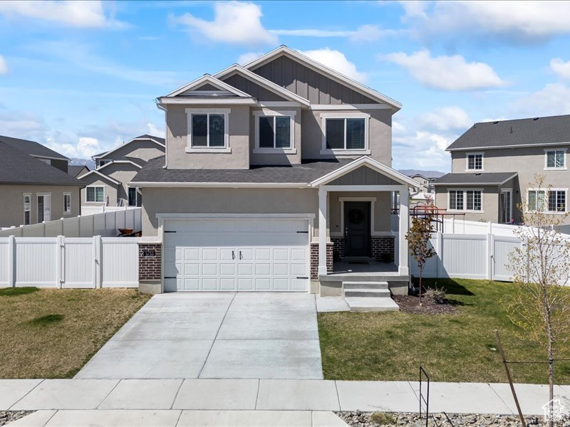 Craftsman inspired home featuring board and batten siding, an attached garage, concrete driveway, stucco siding, and a gate