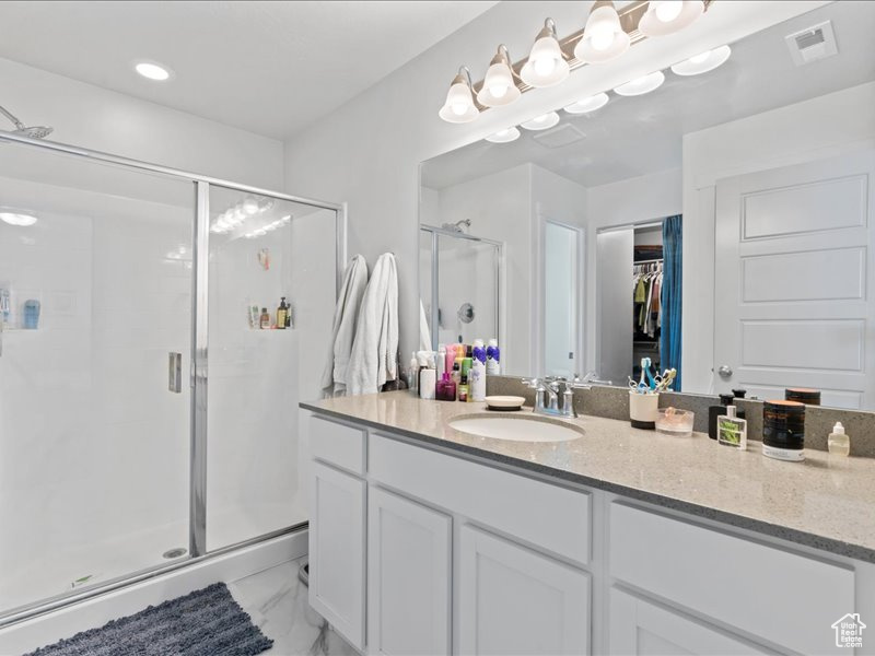 Full bathroom with a shower stall, vanity, a spacious closet, marble finish floors, and recessed lighting