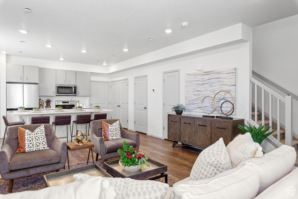Living area featuring dark wood finished floors, stairway, and recessed lighting