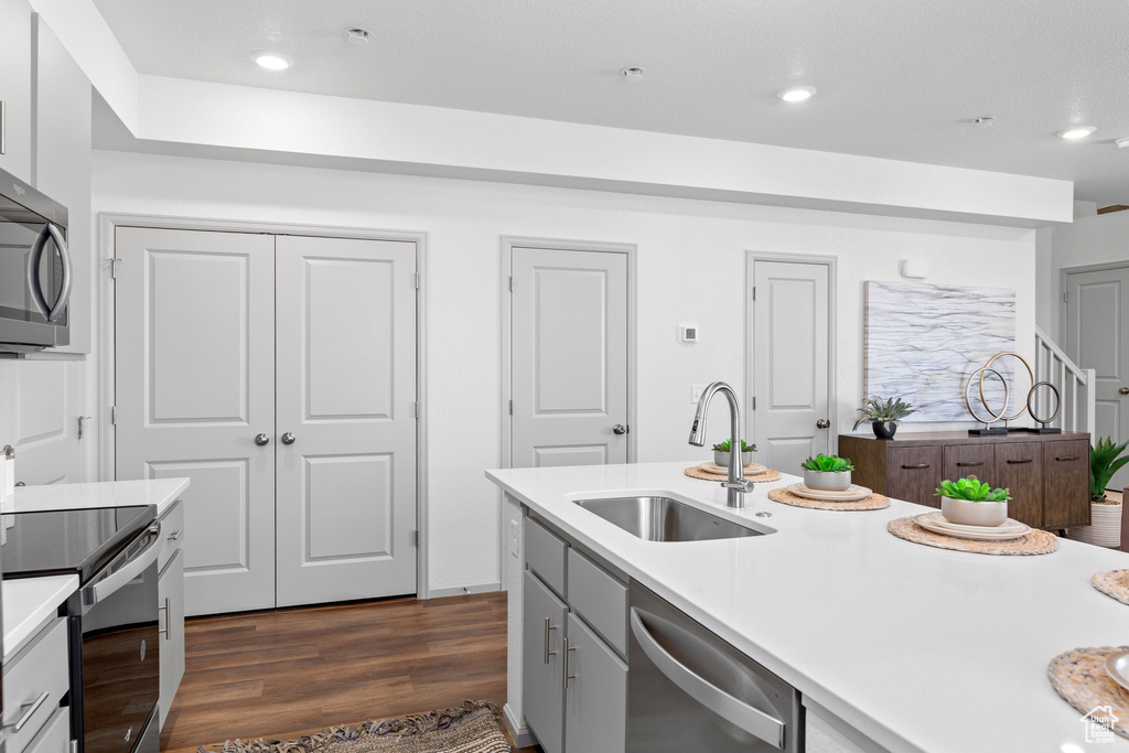Kitchen featuring stainless steel appliances, light countertops, dark wood-type flooring, and recessed lighting