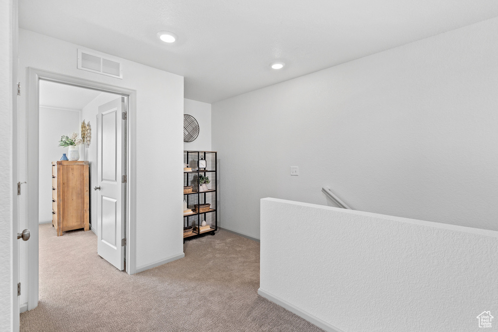 Hallway with light carpet, an upstairs landing, and recessed lighting