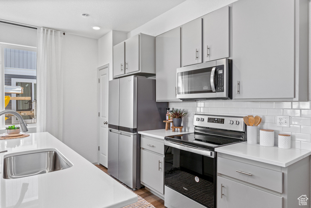 Kitchen featuring appliances with stainless steel finishes, gray cabinetry, light countertops, backsplash, and recessed lighting