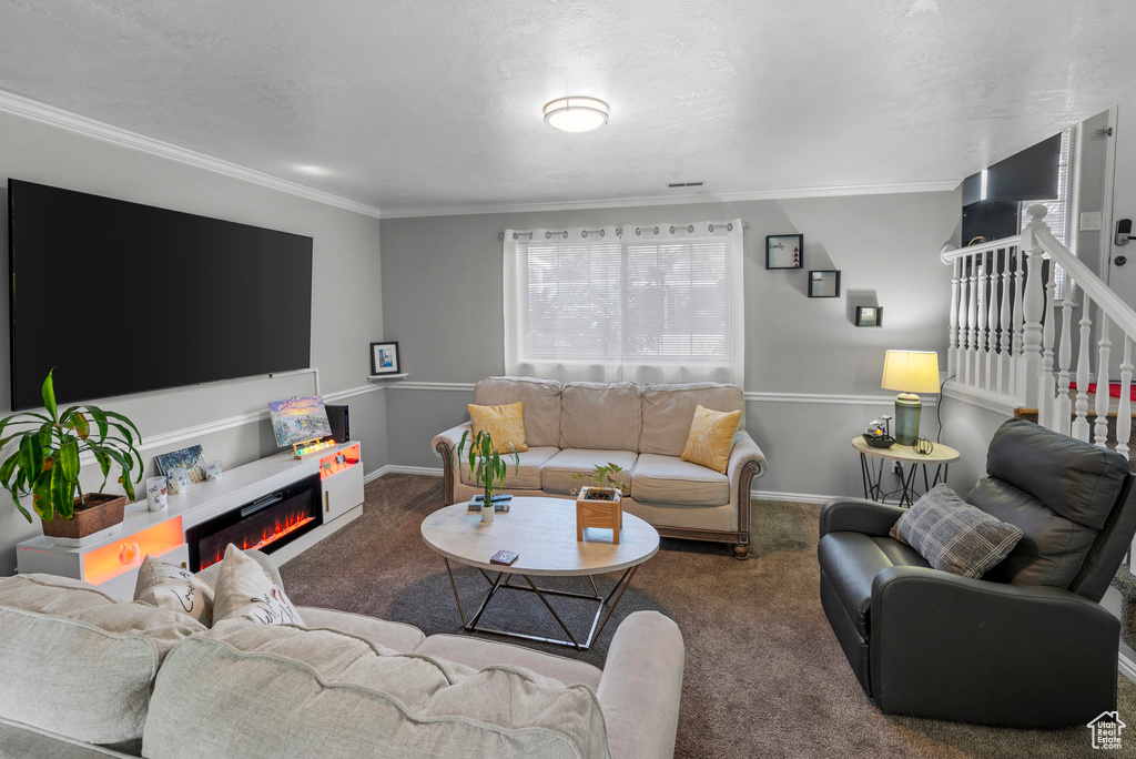 Carpeted living room featuring ornamental molding, stairs, and a glass covered fireplace
