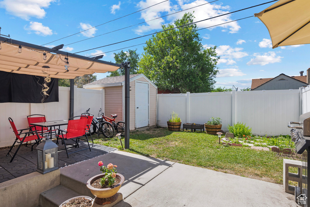 Fenced backyard featuring a patio, a storage unit, and outdoor dining space