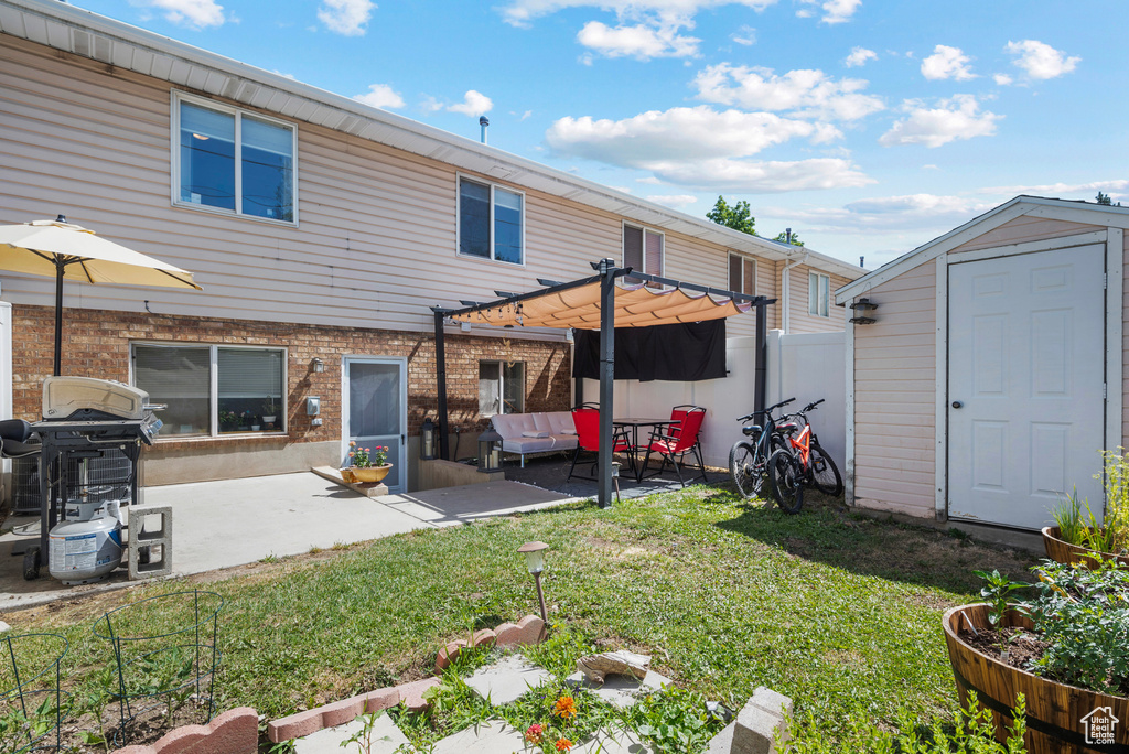 Rear view of house featuring a storage shed, a pergola, and a patio