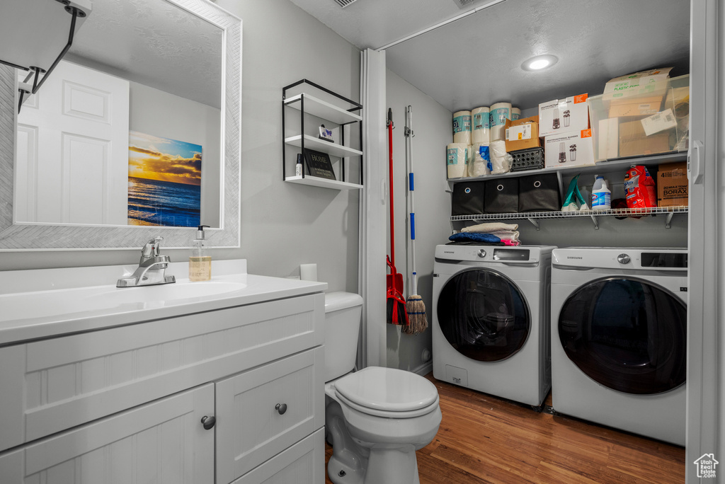 Laundry room featuring washing machine and dryer, wood finished floors, and recessed lighting