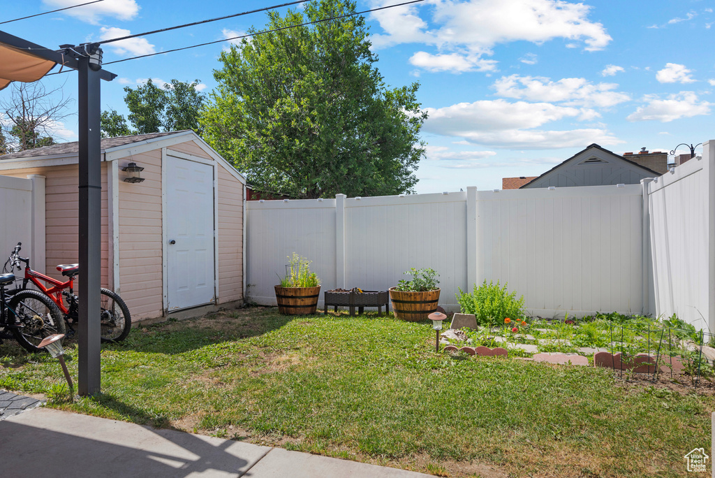 Fenced backyard featuring a storage shed