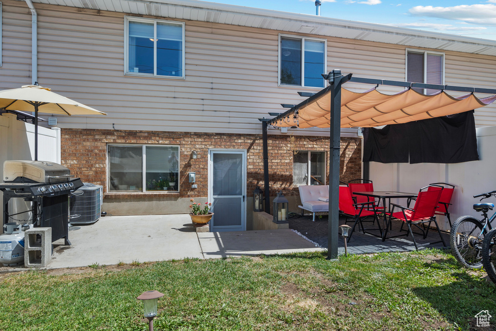Rear view of property with a pergola, a yard, brick siding, and a patio