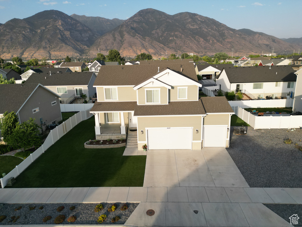View of front of property featuring a residential view, driveway, a fenced backyard, and a garage