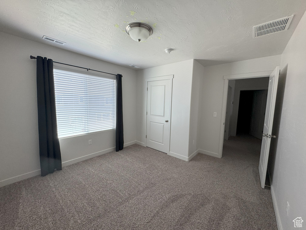 Empty room featuring carpet and a textured ceiling