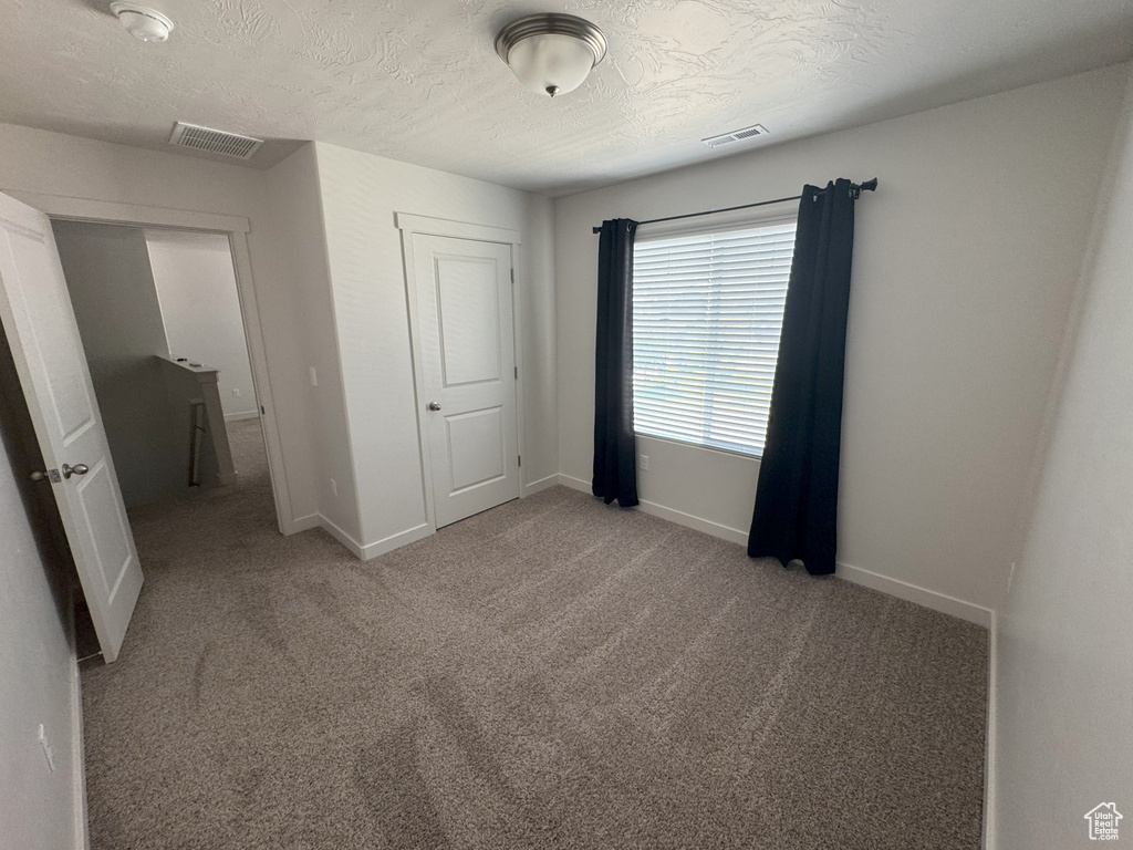 Unfurnished bedroom with carpet floors and a textured ceiling