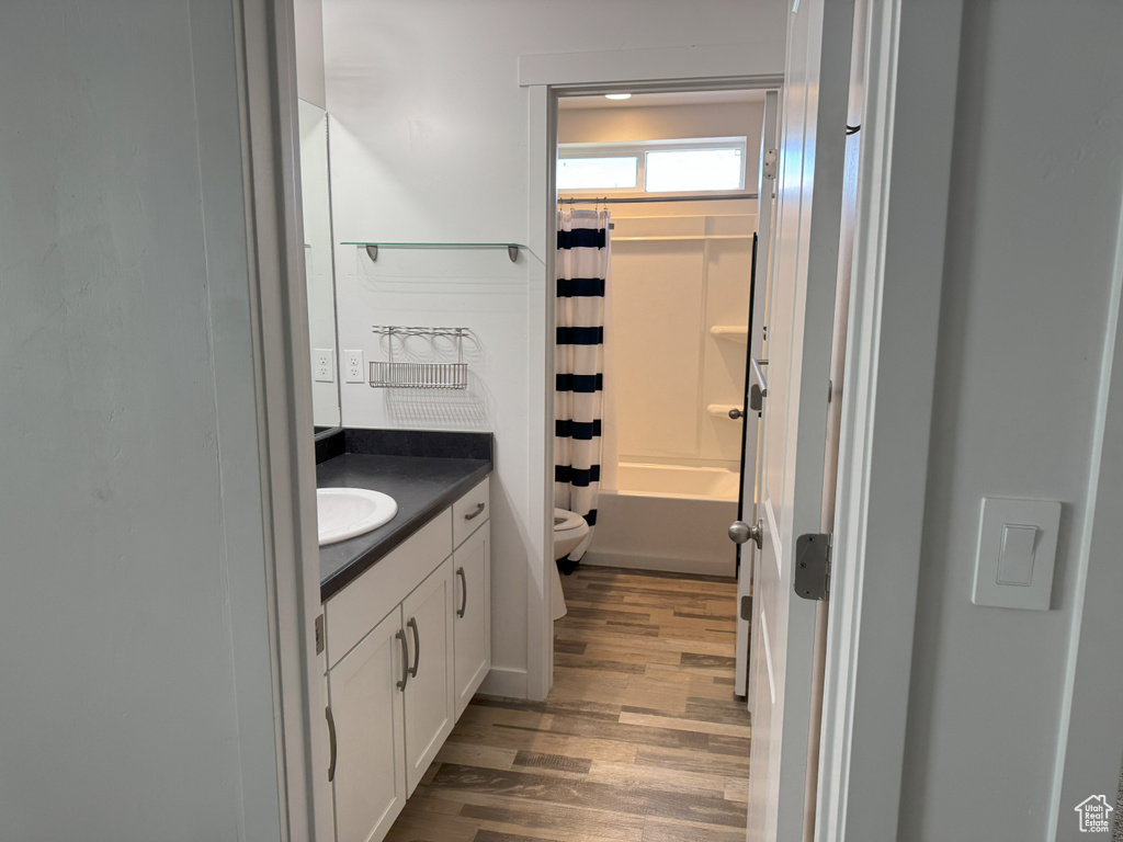 Full bath featuring vanity, wood finished floors, and shower / bath combo with shower curtain