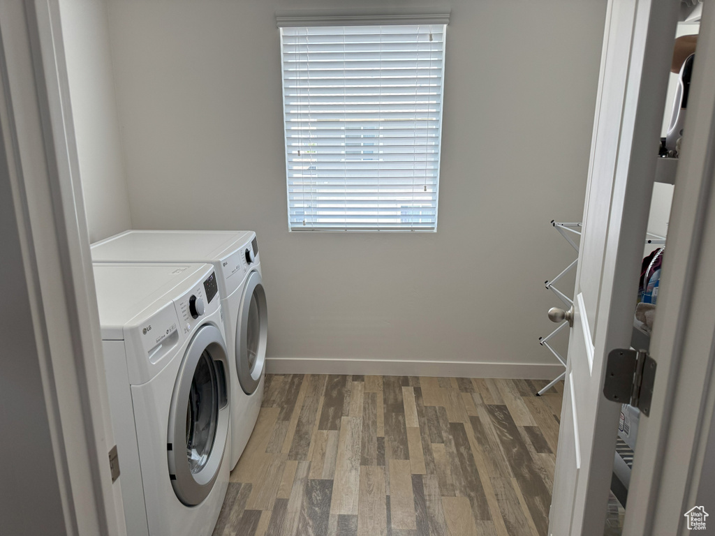 Washroom featuring washing machine and clothes dryer and light wood finished floors