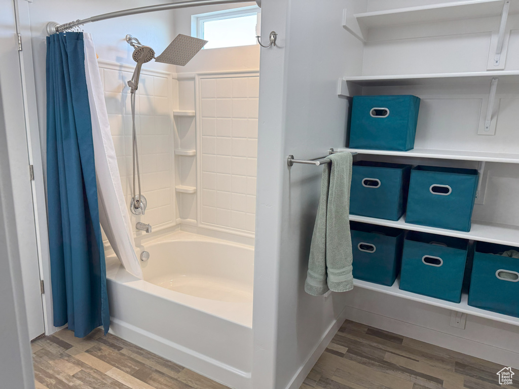 Full bath with shower / bath combo with shower curtain and wood finished floors
