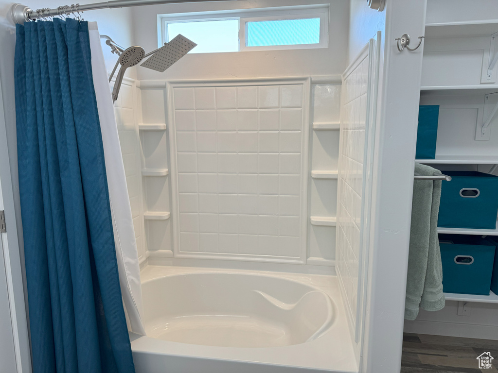 Bathroom with shower / bathtub combination with curtain and wood finished floors
