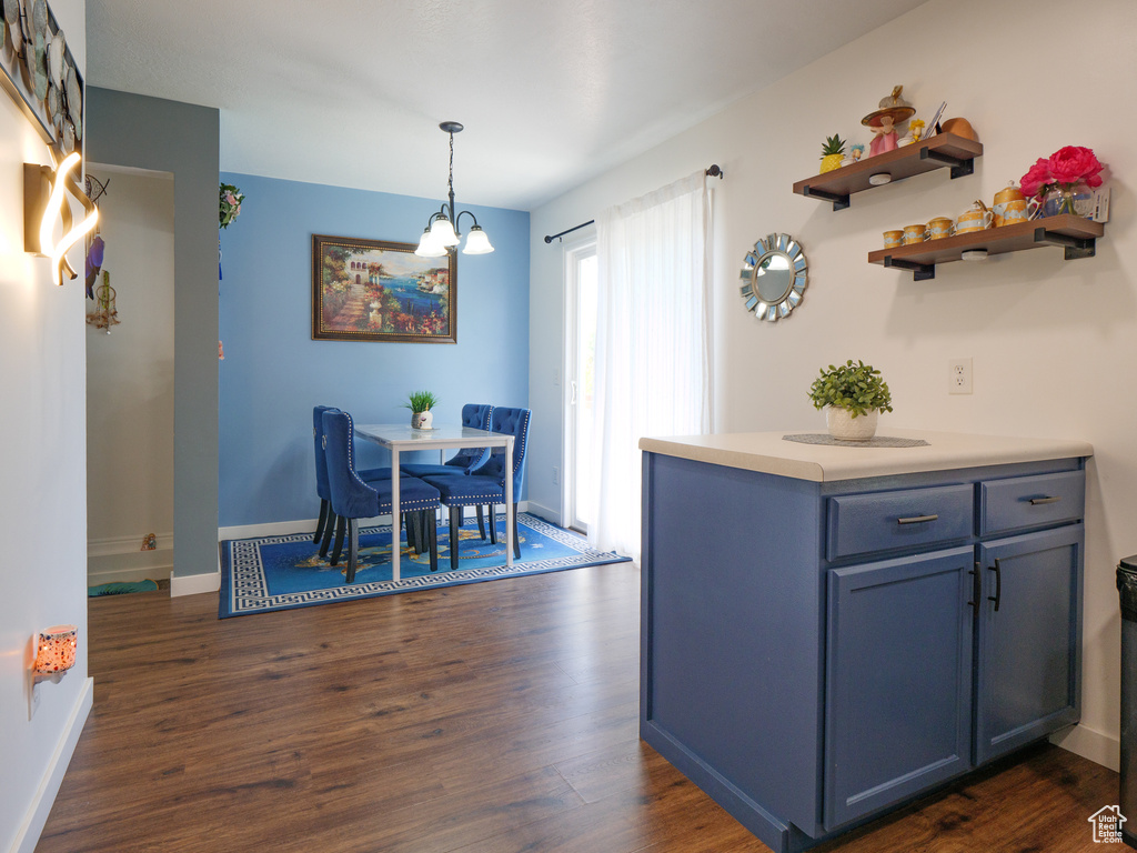 Kitchen with dark wood-style flooring, light countertops, pendant lighting, a chandelier, and open shelves