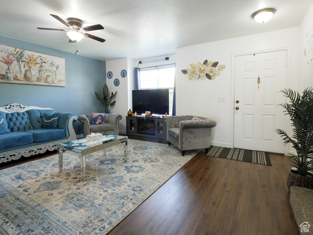 Living room with dark wood finished floors and a ceiling fan