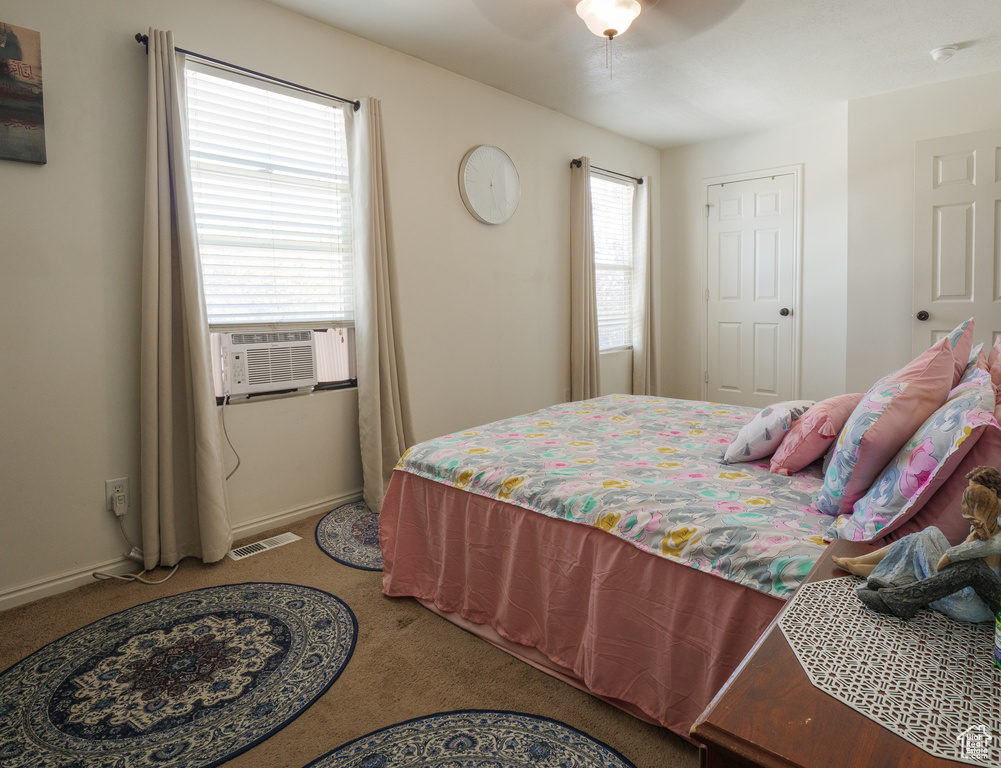 Carpeted bedroom with cooling unit and a ceiling fan