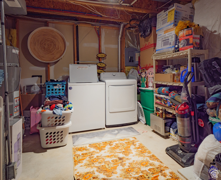 Unfinished below grade area featuring washer and clothes dryer, electric panel, and secured water heater
