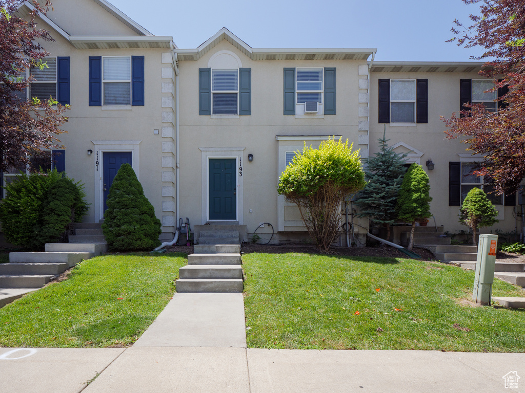Multi unit property featuring stucco siding and a front lawn