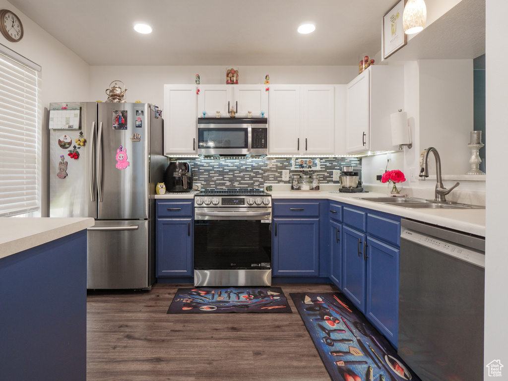 Kitchen featuring appliances with stainless steel finishes, blue cabinetry, light countertops, white cabinets, and recessed lighting