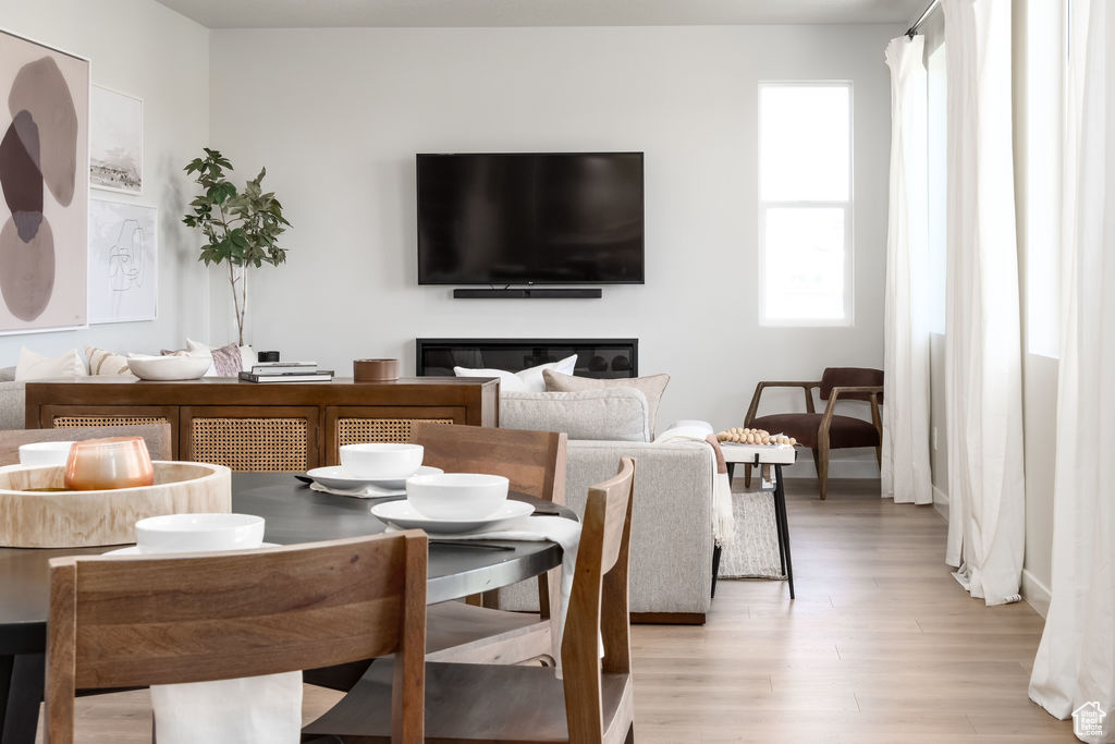 Dining area with light wood finished floors and a glass covered fireplace