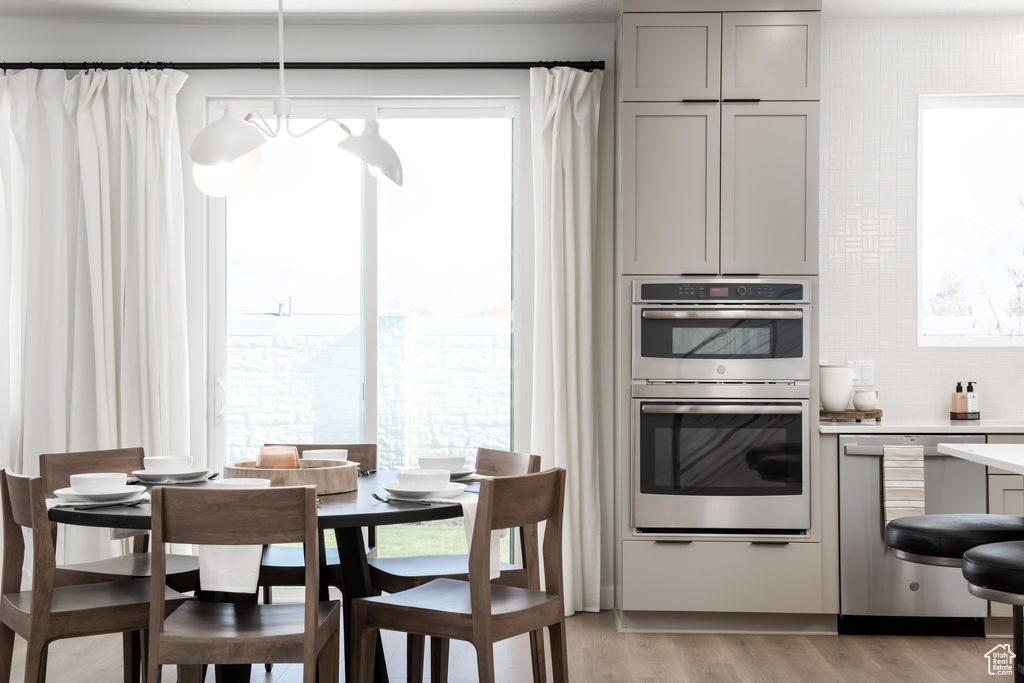 Kitchen featuring gray cabinets, stainless steel appliances, light countertops, light wood finished floors, and decorative backsplash