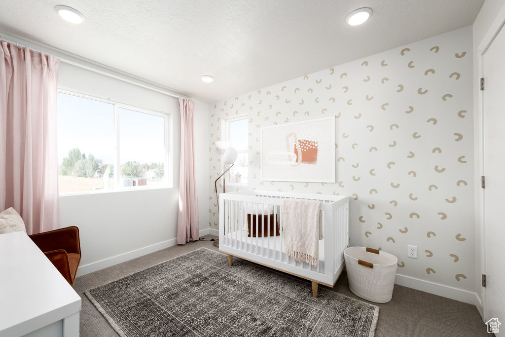 Bedroom with carpet flooring, wallpapered walls, a crib, and recessed lighting