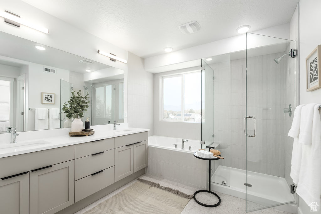 Full bathroom featuring a bath, a shower stall, double vanity, and recessed lighting