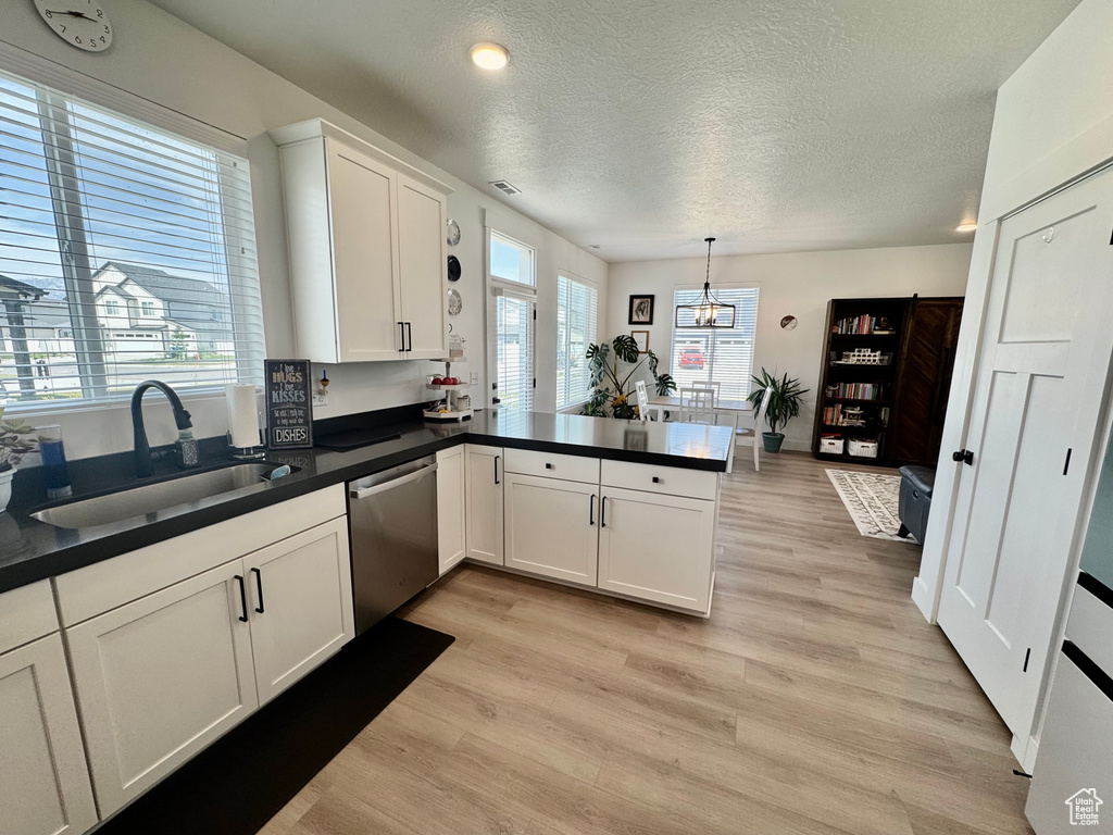 Kitchen featuring dishwasher, light wood-style flooring, a peninsula, white cabinets, and a textured ceiling