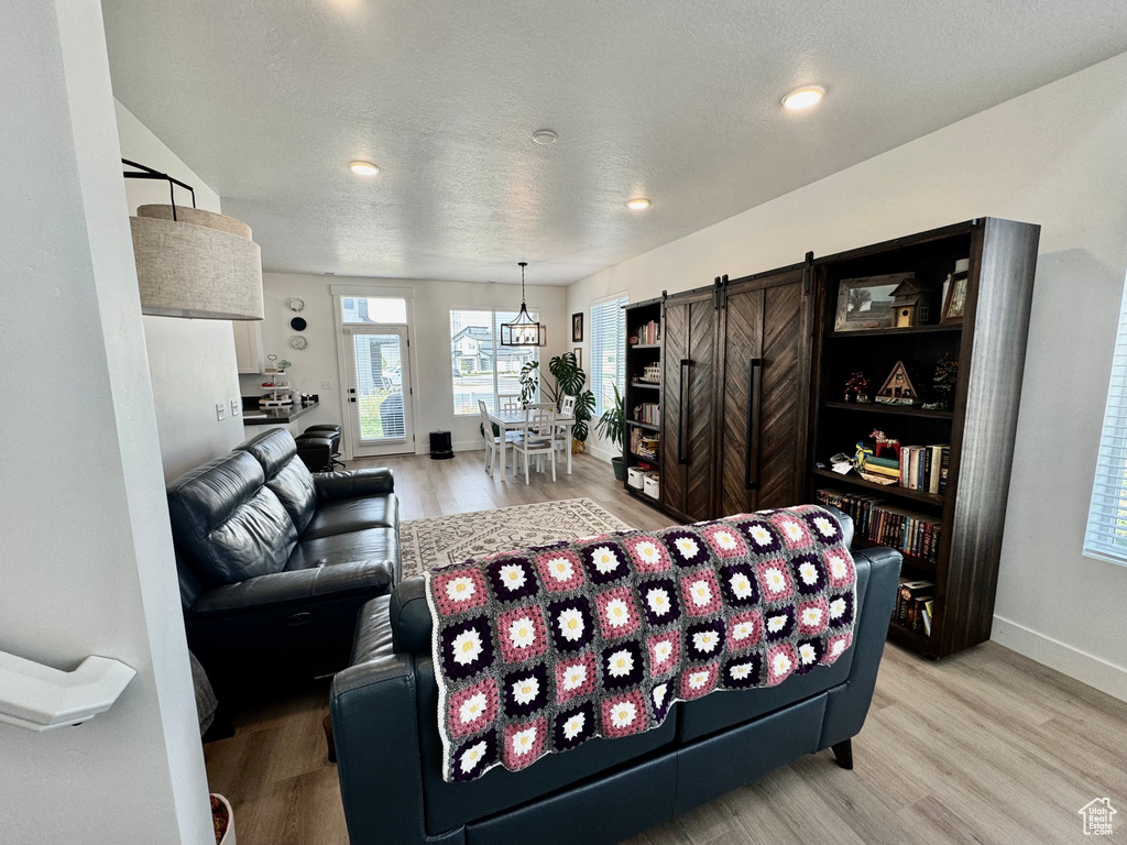 Living area with a barn door, light wood-style flooring, recessed lighting, and a textured ceiling