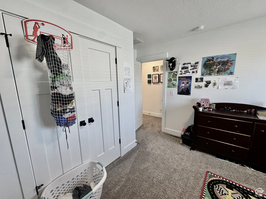 Carpeted bedroom with a textured ceiling and baseboards