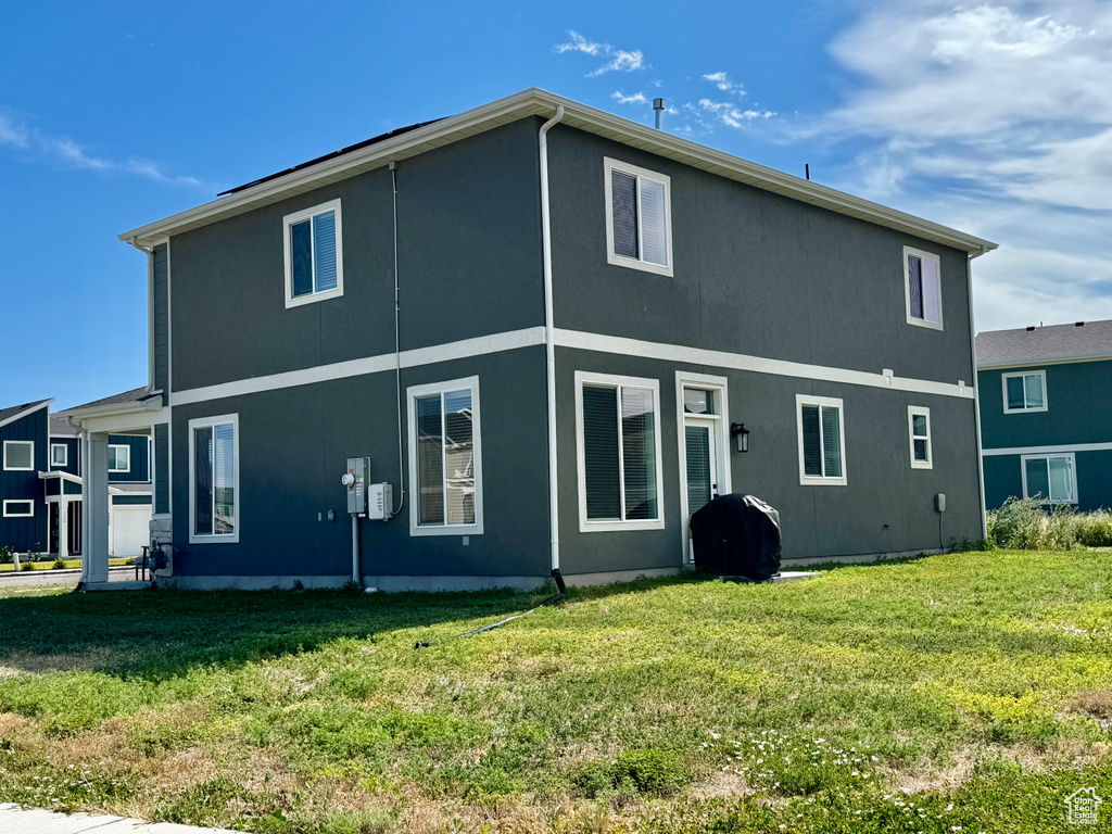 Back of house featuring a yard and stucco siding