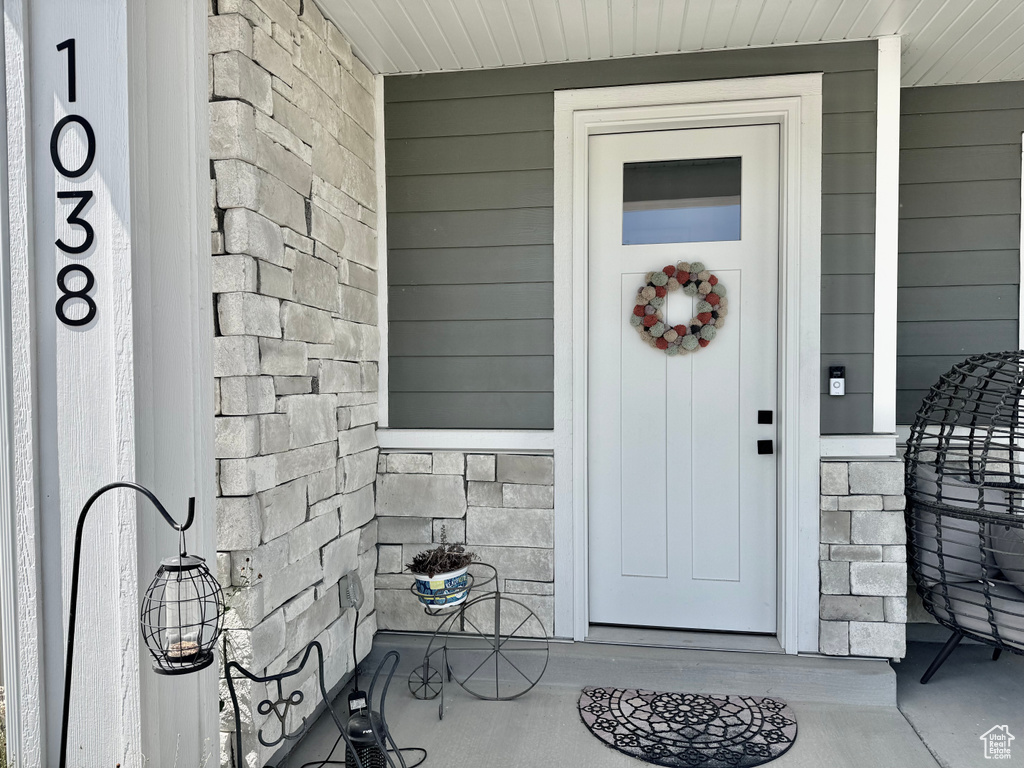 View of exterior entry with stone siding and a porch