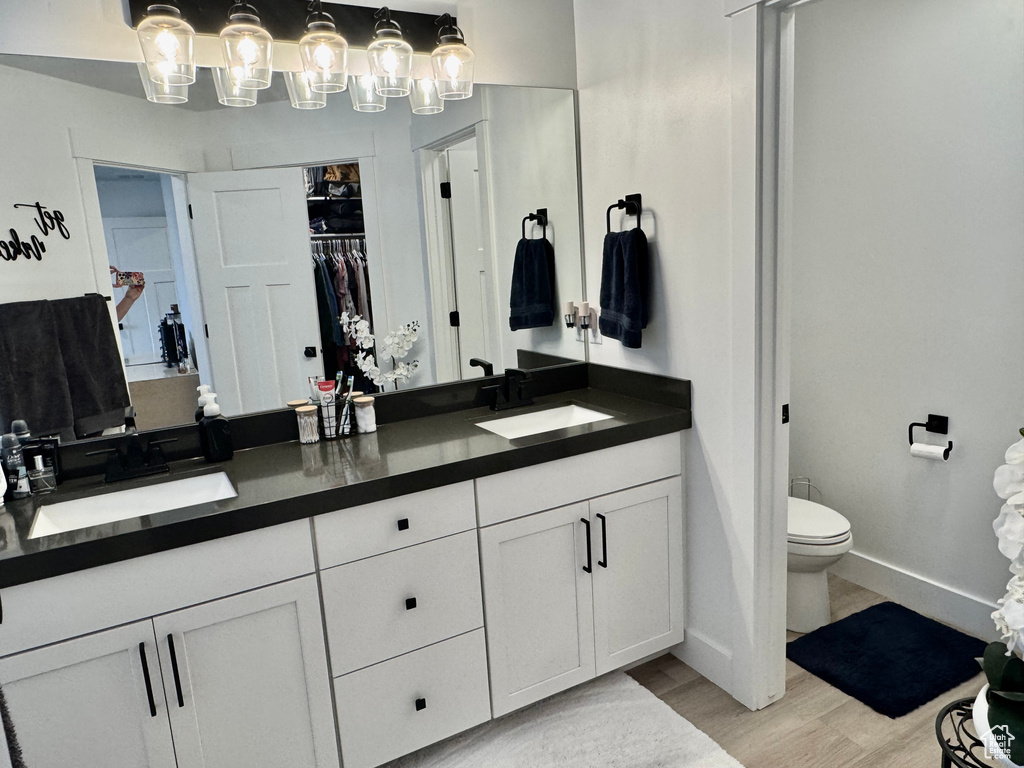 Bathroom with double vanity, wood finished floors, and a walk in closet