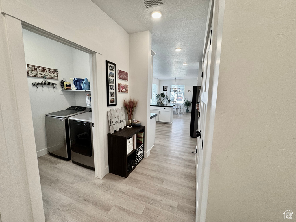 Corridor featuring washer and clothes dryer, light wood-type flooring, a textured ceiling, and recessed lighting